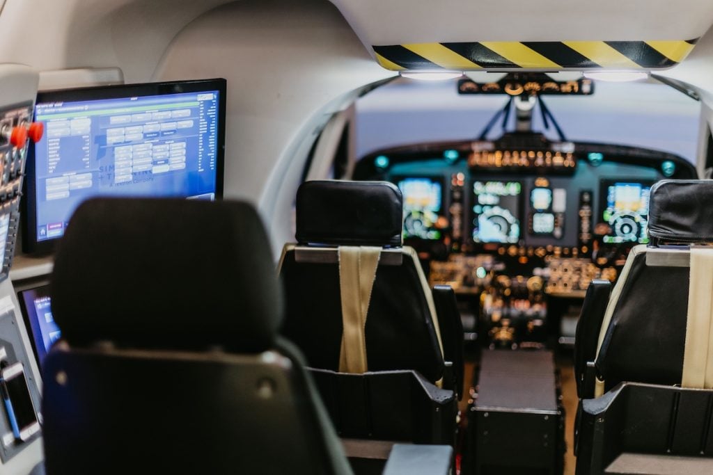 Aircraft cockpit interior with control panels and seats.