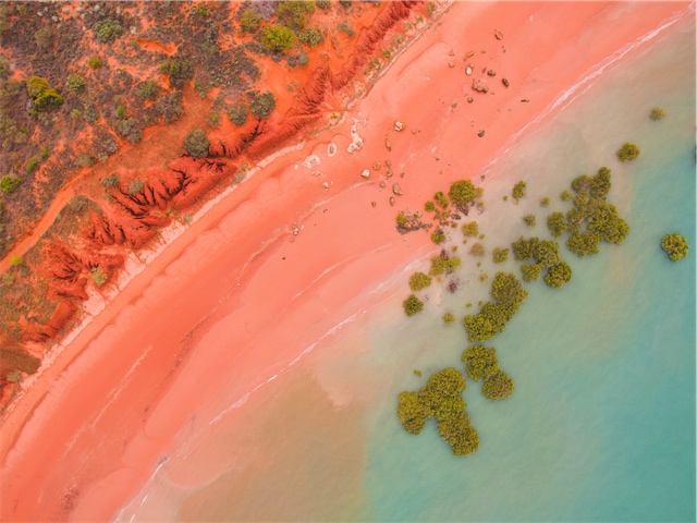 Aerial view of red beach and turquoise water.
