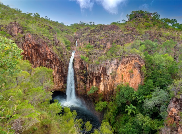 Waterfall cascading through lush green landscape.