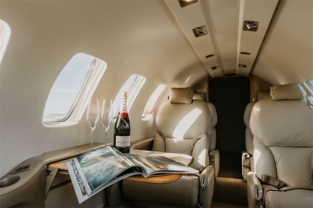Private jet interior with champagne and magazine.