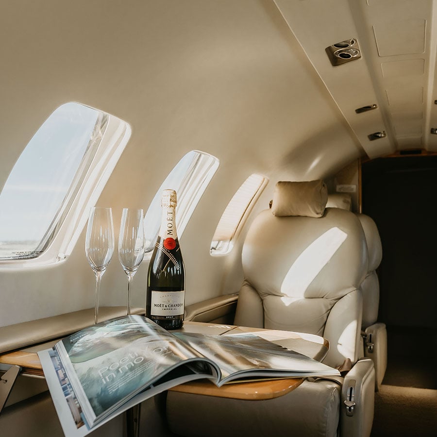 Luxury private jet flight, with champagne and magazine on a table.