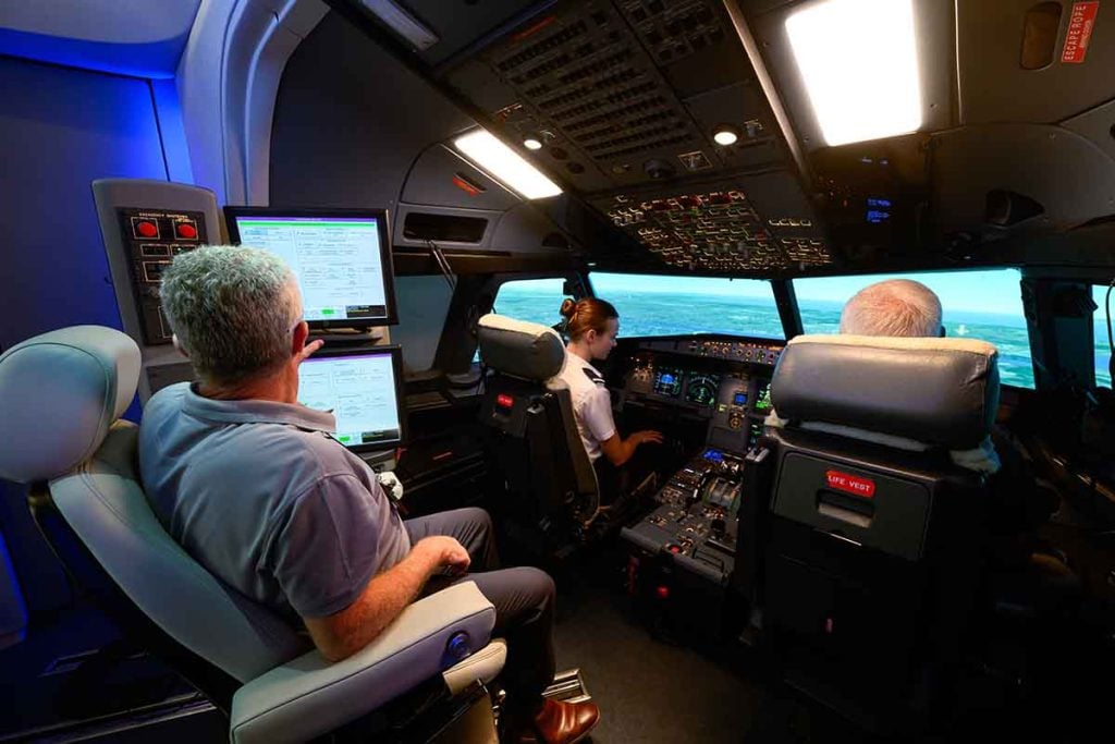Aircraft flight simulator cockpit with pilot and instructor doing the Multi Crew Cooperation Course (MCC)