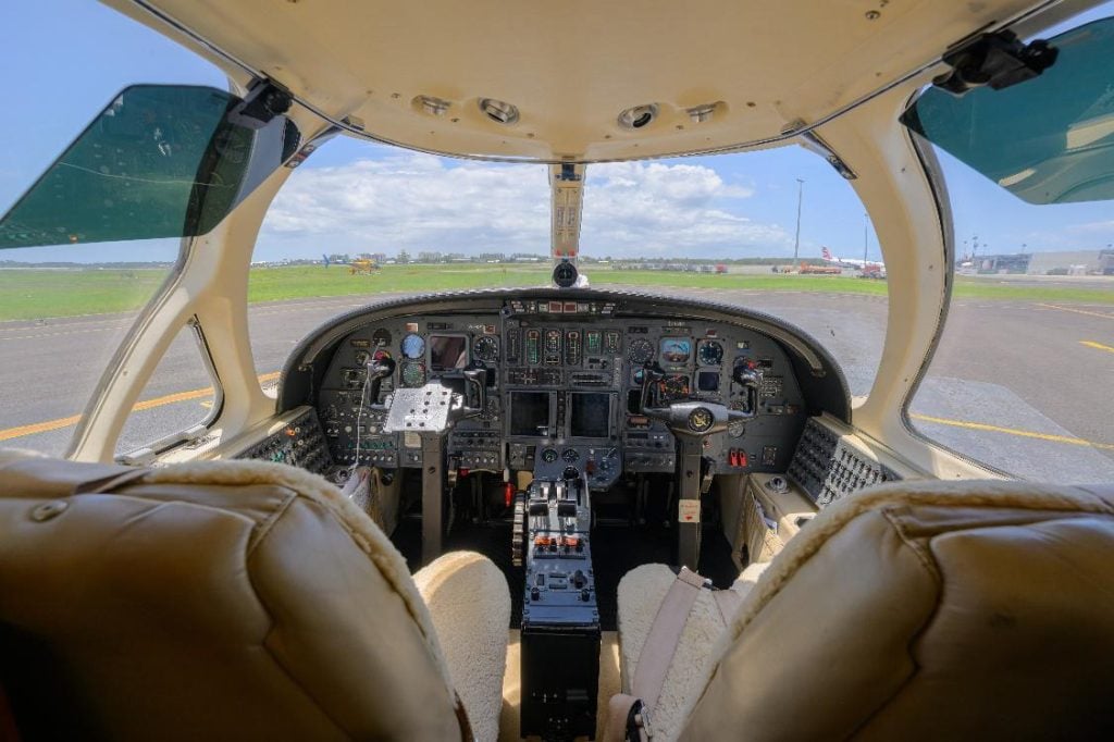 Airplane cockpit view, airfield outside.