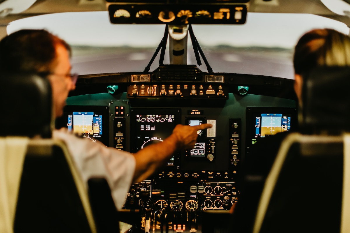 Pilots in airplane cockpit operating controls as part of a recurrent training course.
